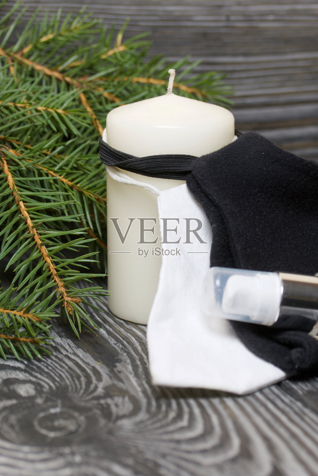 杉树枝和一支蜡烛。附近有医用口罩和杀菌剂。在黑色的松木板上。照片摄影图片