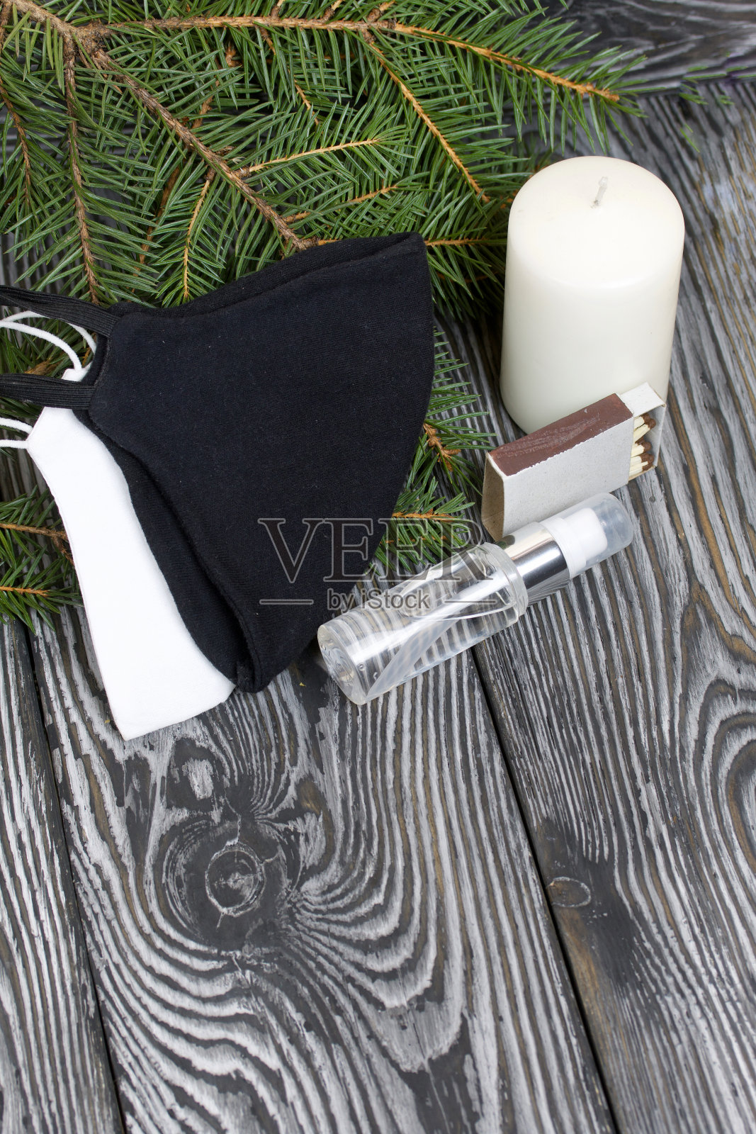杉树枝和一支蜡烛。附近有医用口罩和杀菌剂。在黑色的松木板上。照片摄影图片