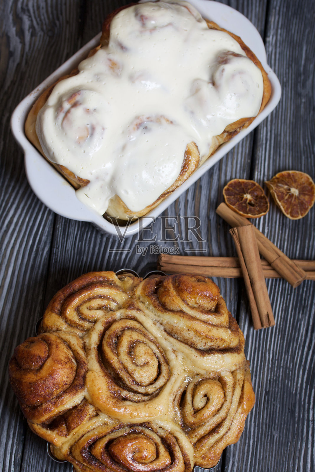 烤肉桂饼的形状。有些上釉。站在黑色的复合板上。附近是肉桂棒。特写镜头。照片摄影图片