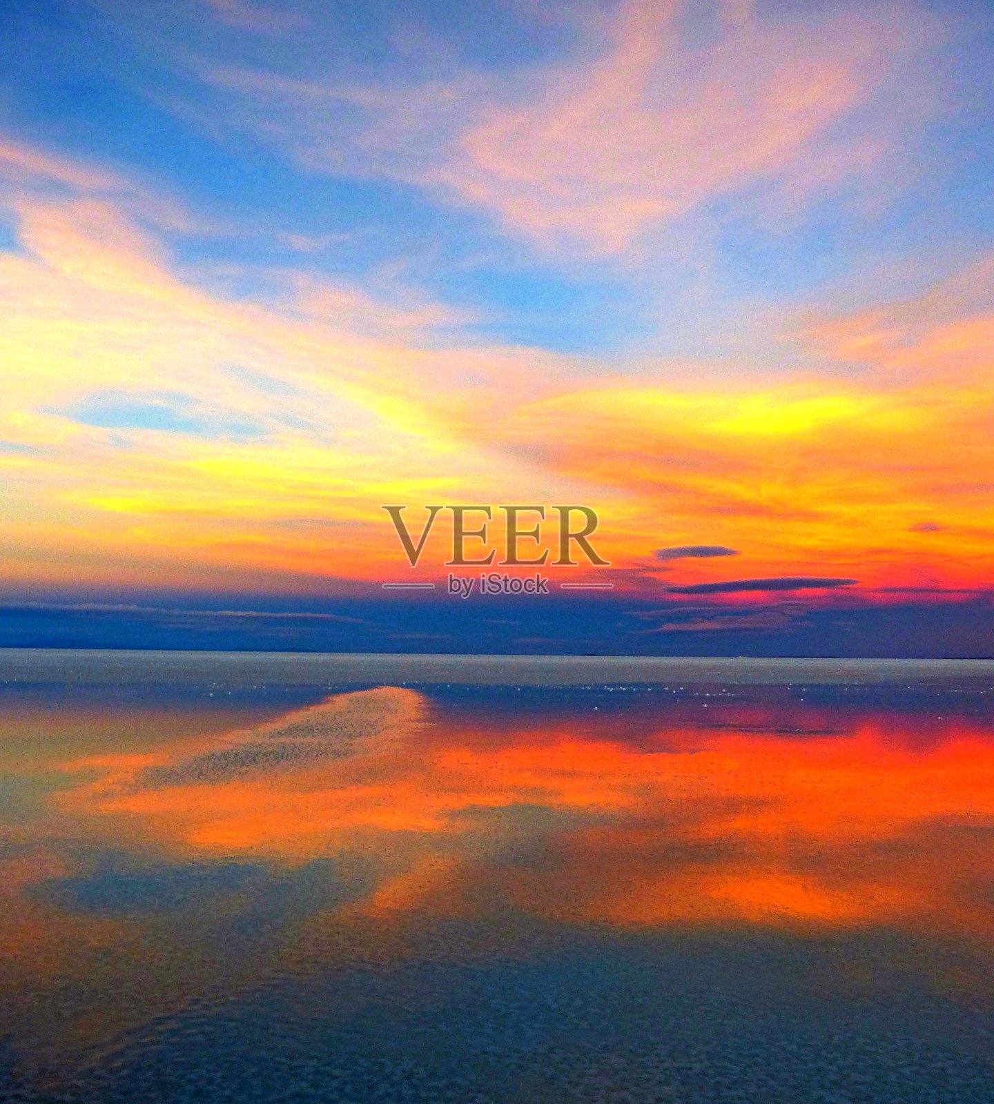 明亮多彩的日落，神奇的云彩反射在宁静的湖水，火红的金色天空，自然奇迹在独特的盐滩乌尤尼盐湖，沙漠黄昏。照片摄影图片