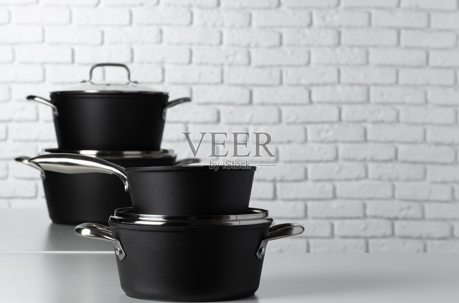 靠白砖墙的桌子上放着一套炊具照片摄影图片