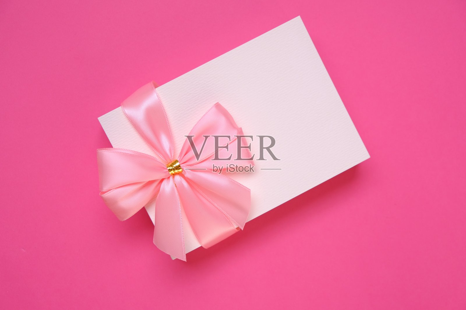 明信片空白。节日贺卡与粉红色蝴蝶结在明亮的粉红色背景。生日空白明信片。妇女节，母亲节，情人节。副本的空间。照片摄影图片