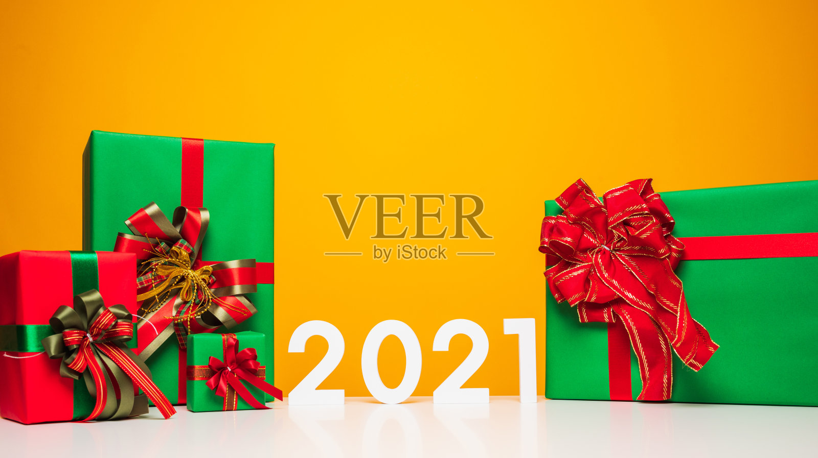 圣诞快乐，新年快乐2021白色桌子和黄色背景与礼物盒模型。庆祝与新年模板和空白背景广告。照片摄影图片