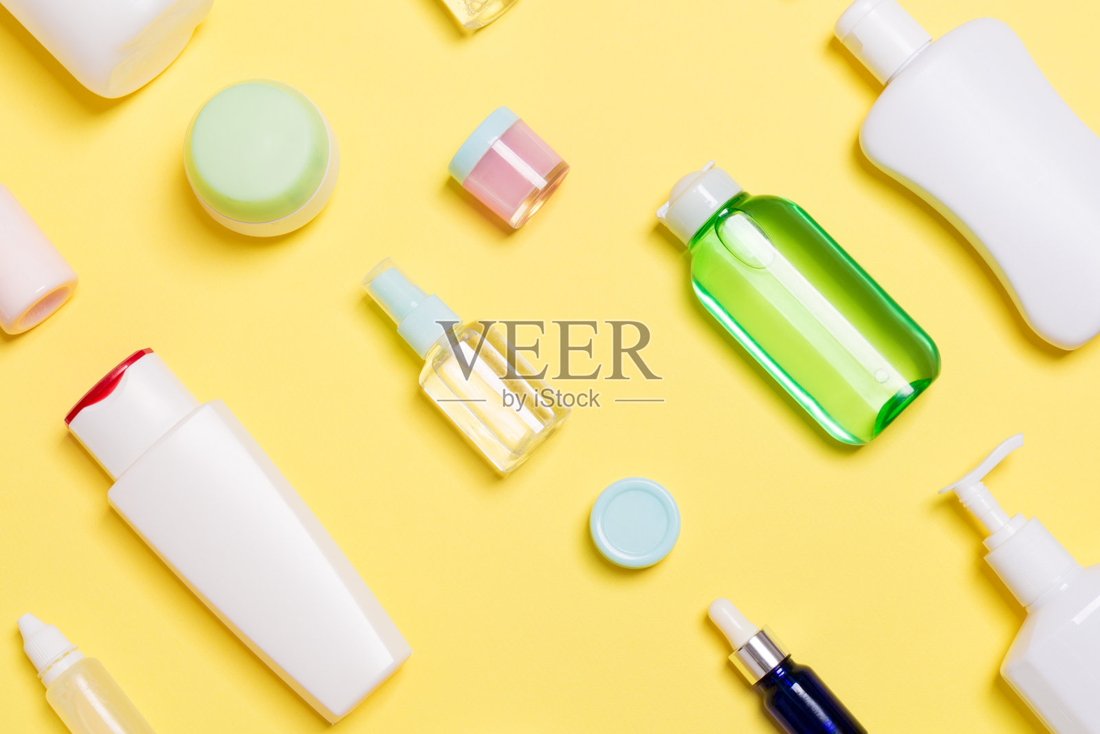 俯视图不同化妆品瓶和容器上的黄色背景化妆品。平铺构图与复制空间照片摄影图片