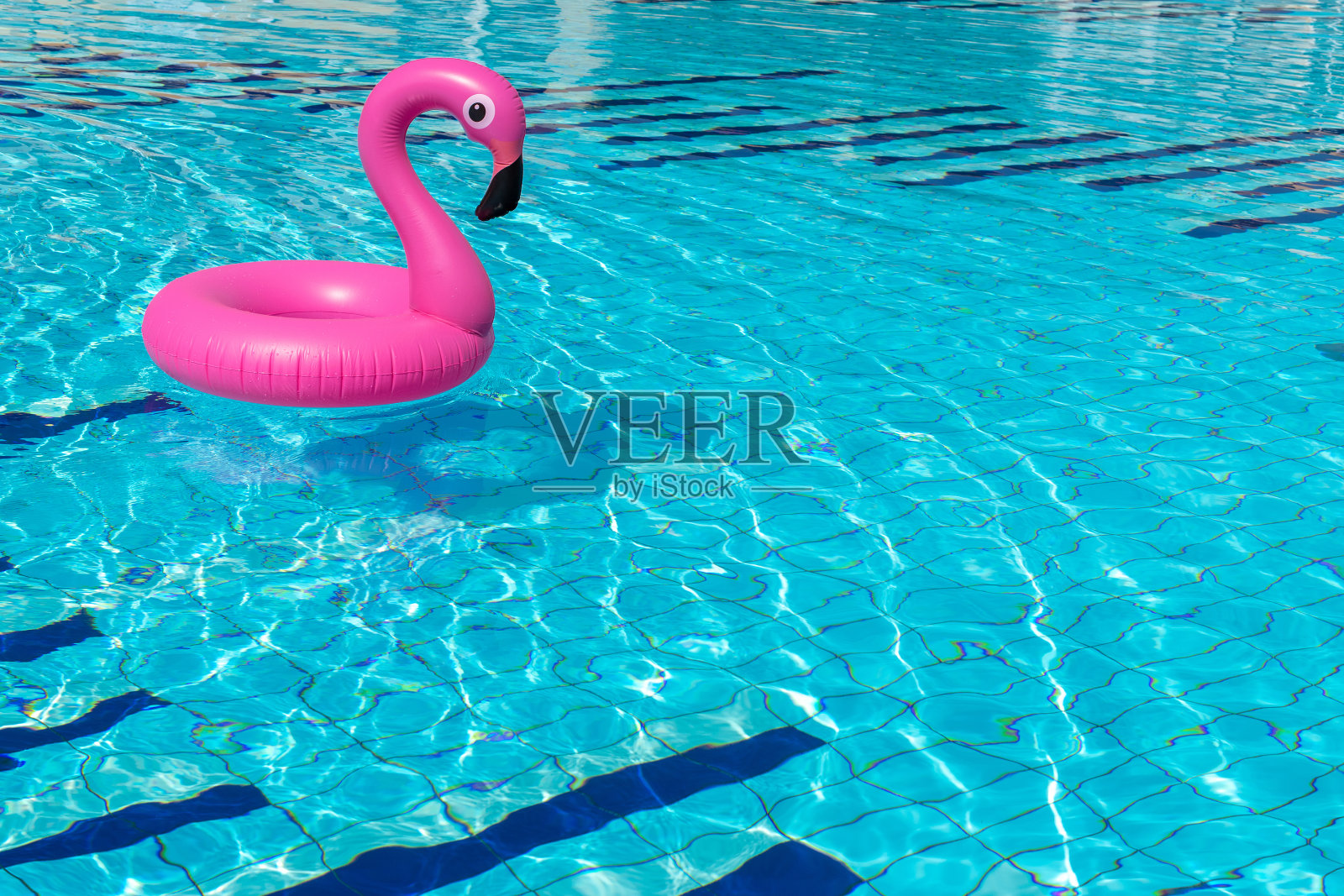 夏天概念背景。粉红色的充气火烈鸟在游泳池的水为夏天的海滩背景。池浮动。照片摄影图片