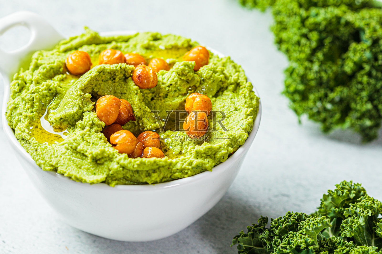 白碗里的绿甘蓝鹰嘴豆泥。素食鹰嘴豆泡。健康素食理念。照片摄影图片