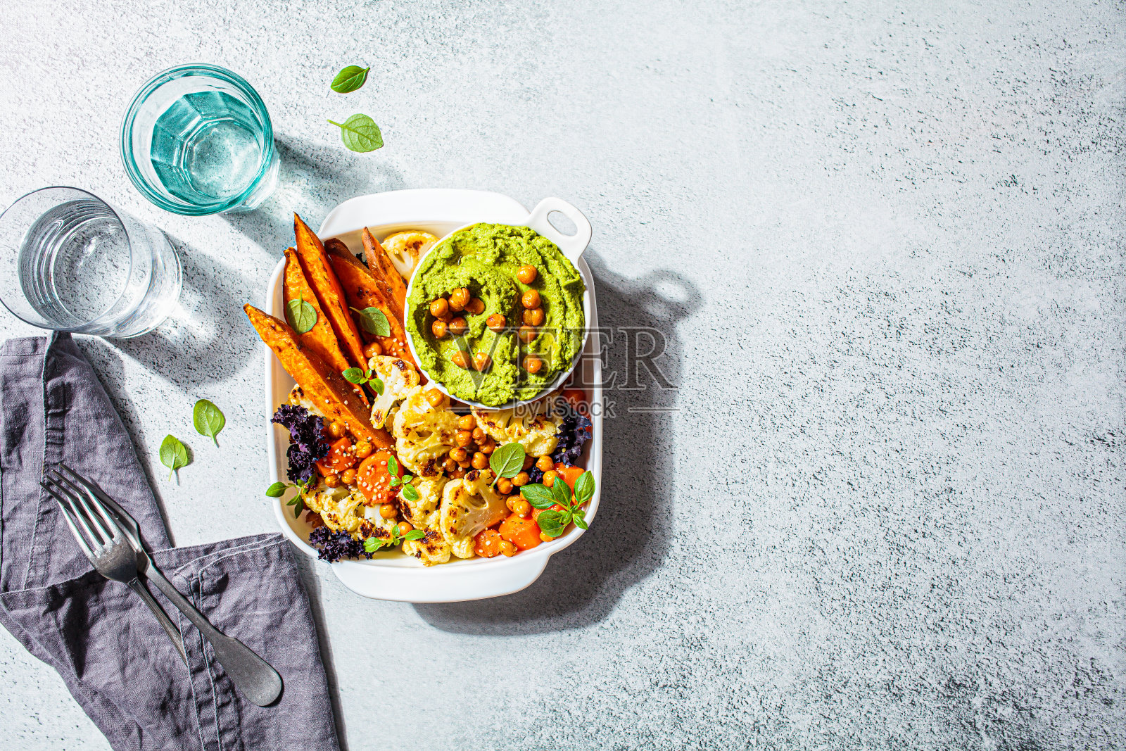 素食的概念。烤蔬菜与绿羽衣甘蓝鹰嘴豆泥，浅背景。夏季健康食品。照片摄影图片