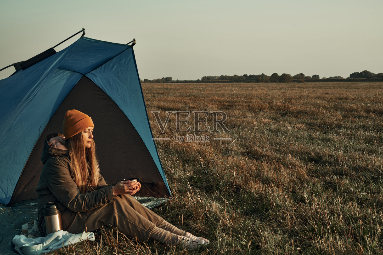 女孩用杯子喝水，看着寒冷的黎明。旅行。照片摄影图片