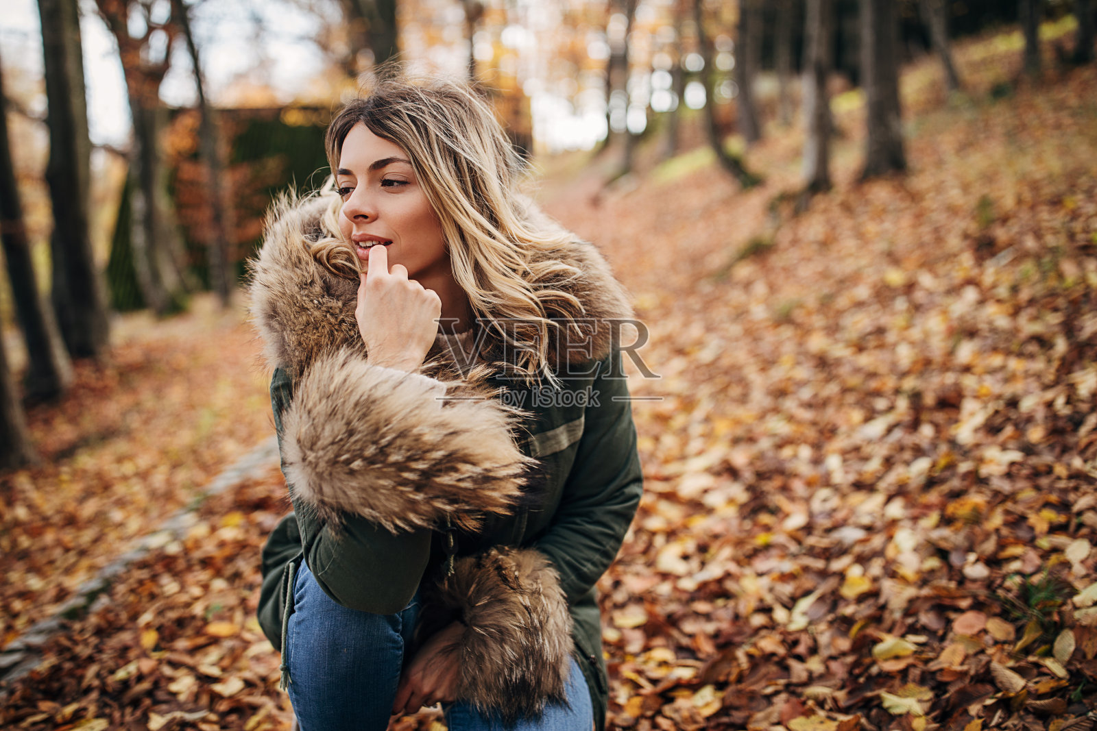 年轻女子跪在秋天的森林里照片摄影图片