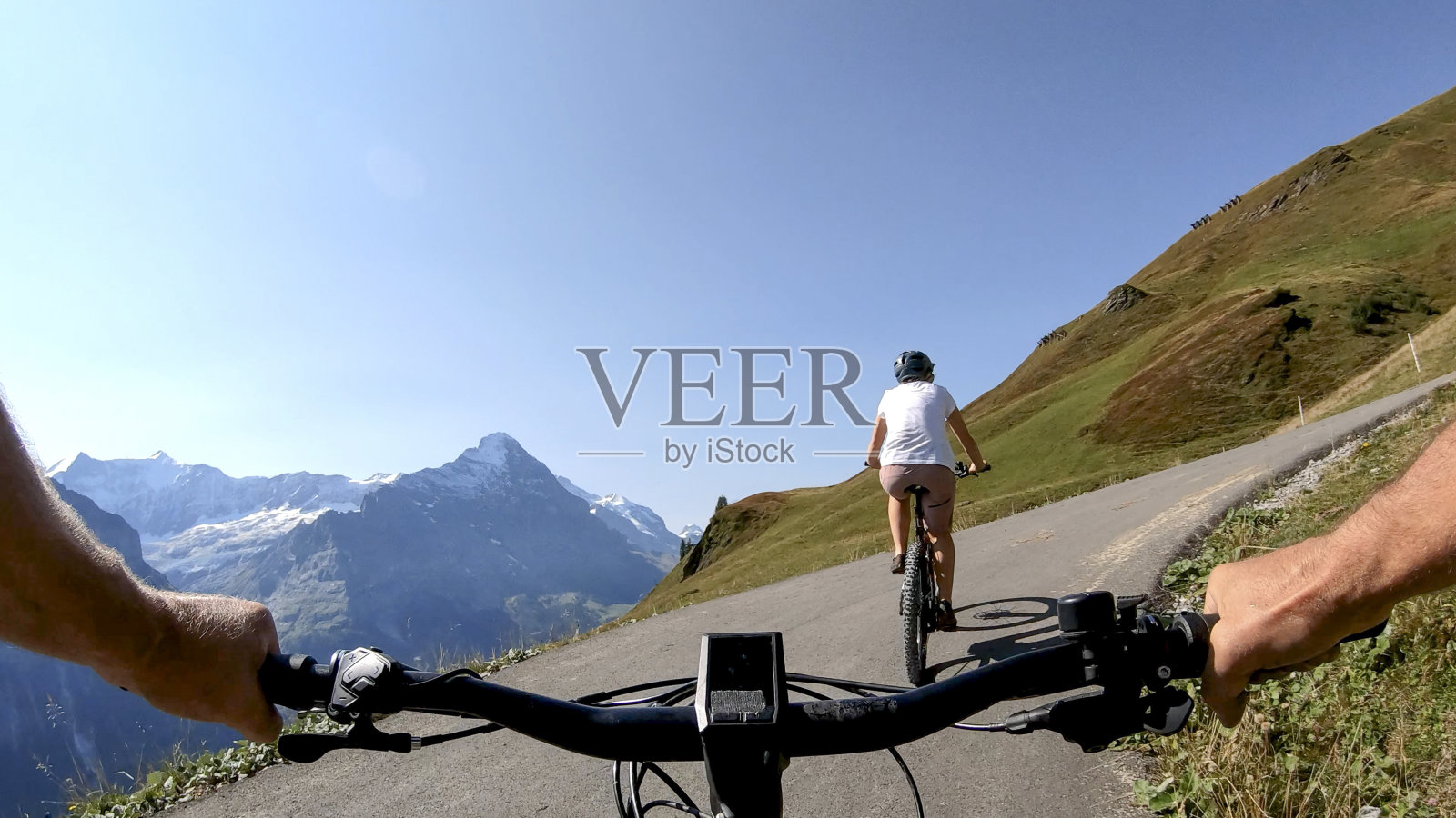 POV透视沿山坡电动自行车后面的一个年轻女子山地自行车照片摄影图片