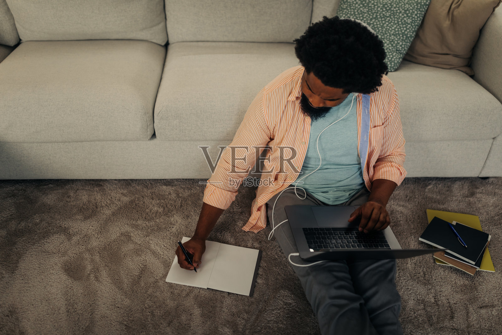 年轻黑人戴着耳机坐在地板上用笔记本电脑照片摄影图片