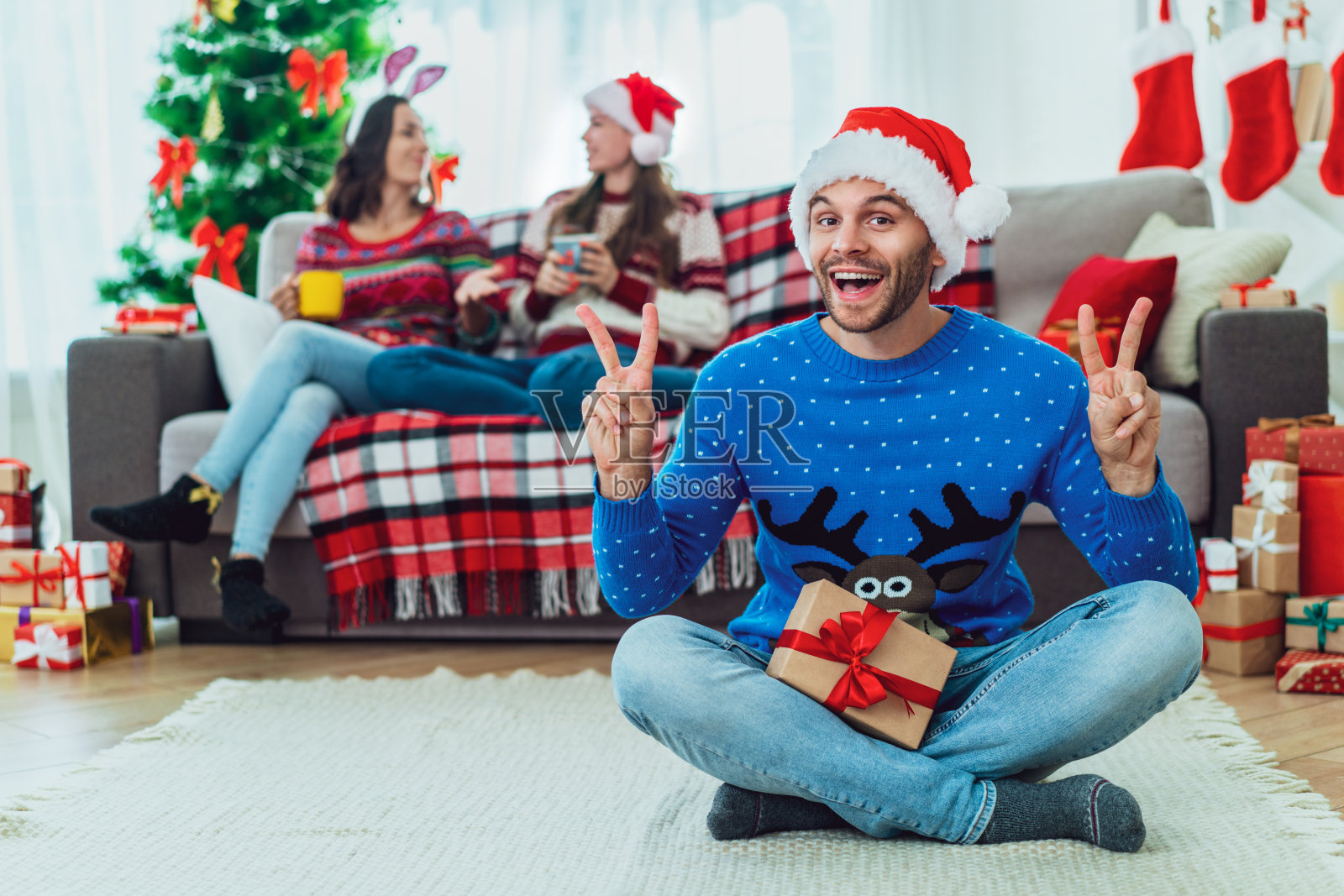 最好的朋友在家里欢度寒假，坐在舒适的沙发上拆礼物照片摄影图片