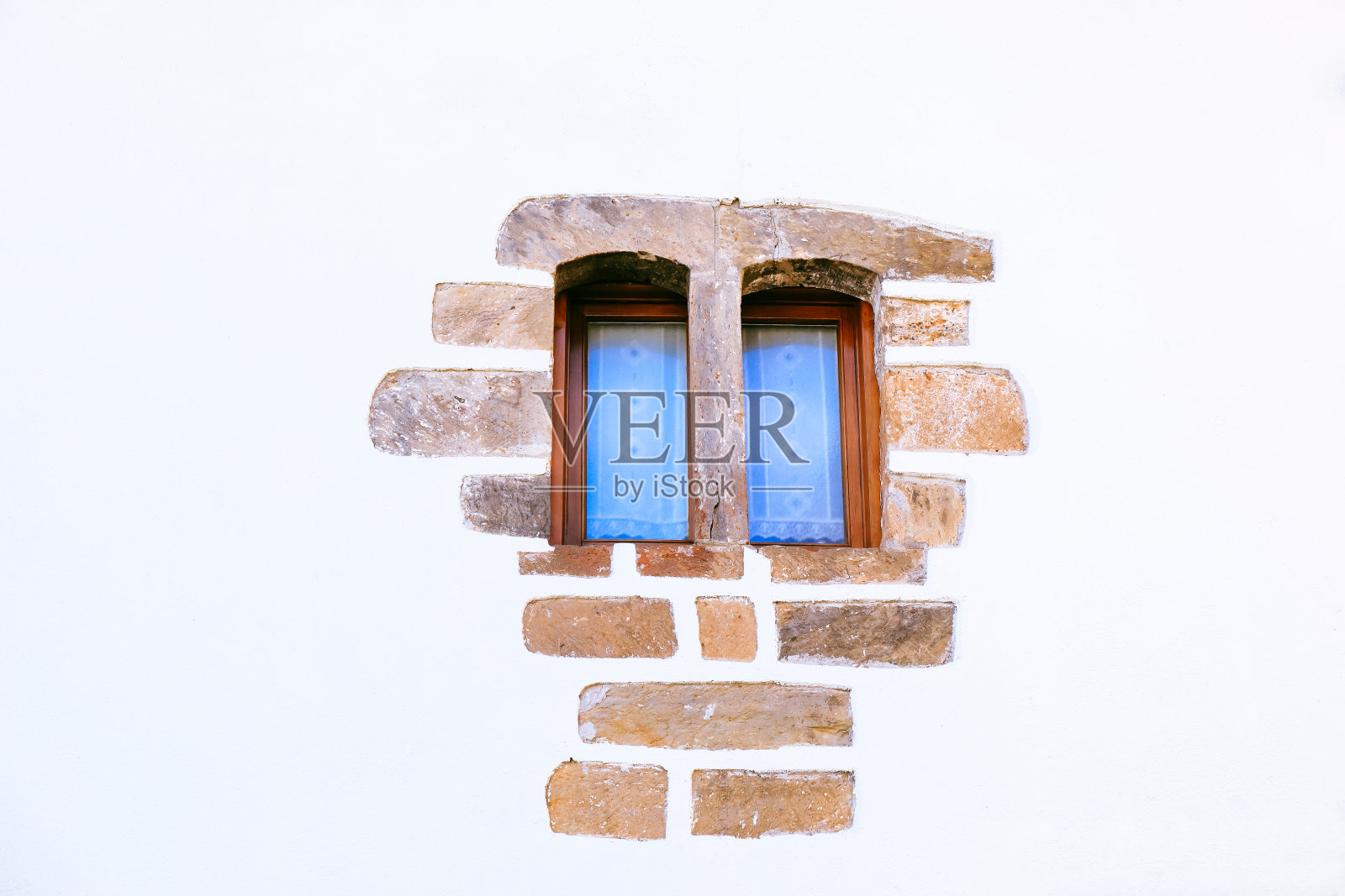 白色墙壁上的双扇窗户，带有石材装饰的老房子照片摄影图片