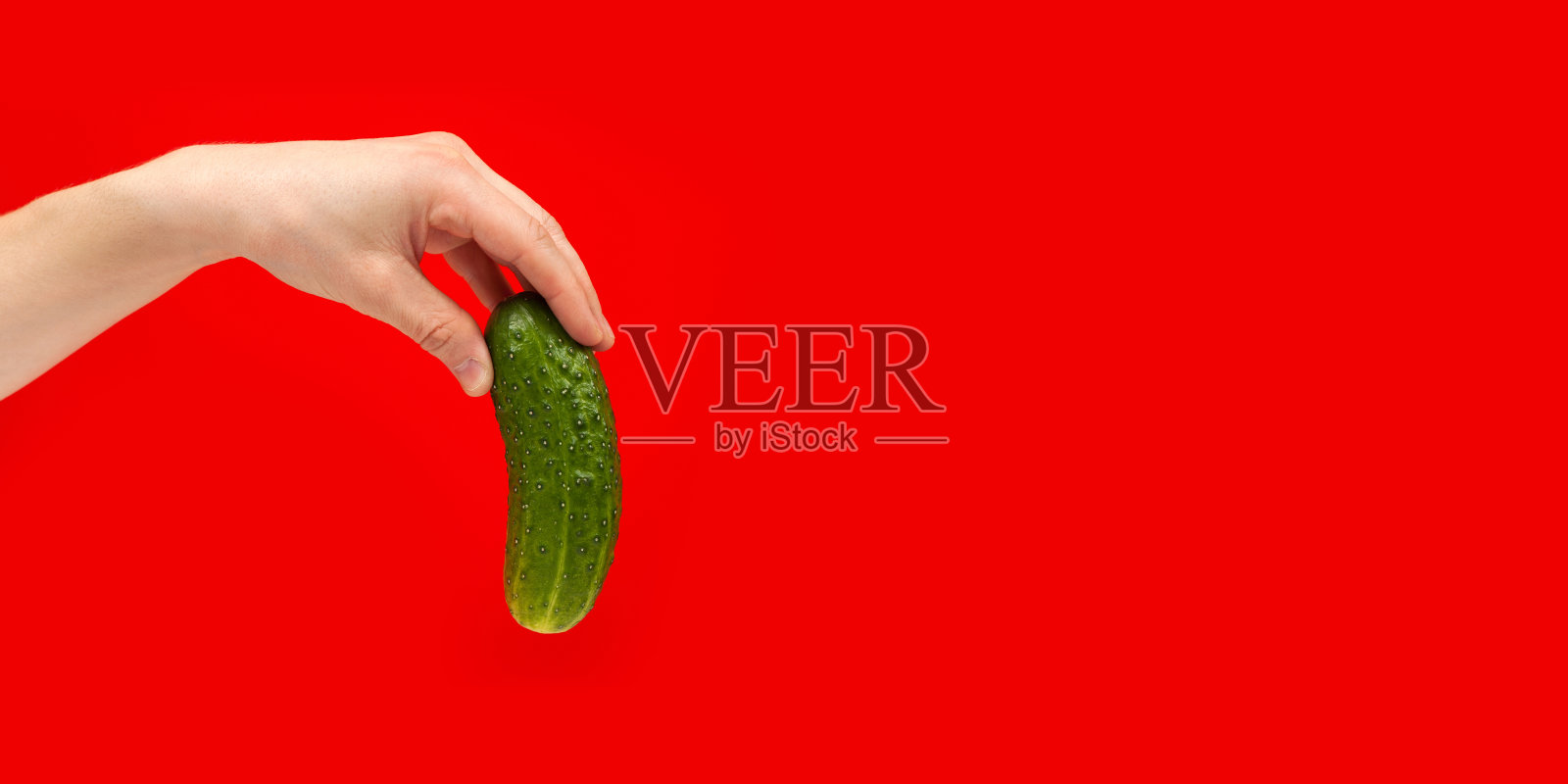 成熟多汁美味的黄瓜手孤立在红色背景。健康饮食与节食观念。本空间照片摄影图片