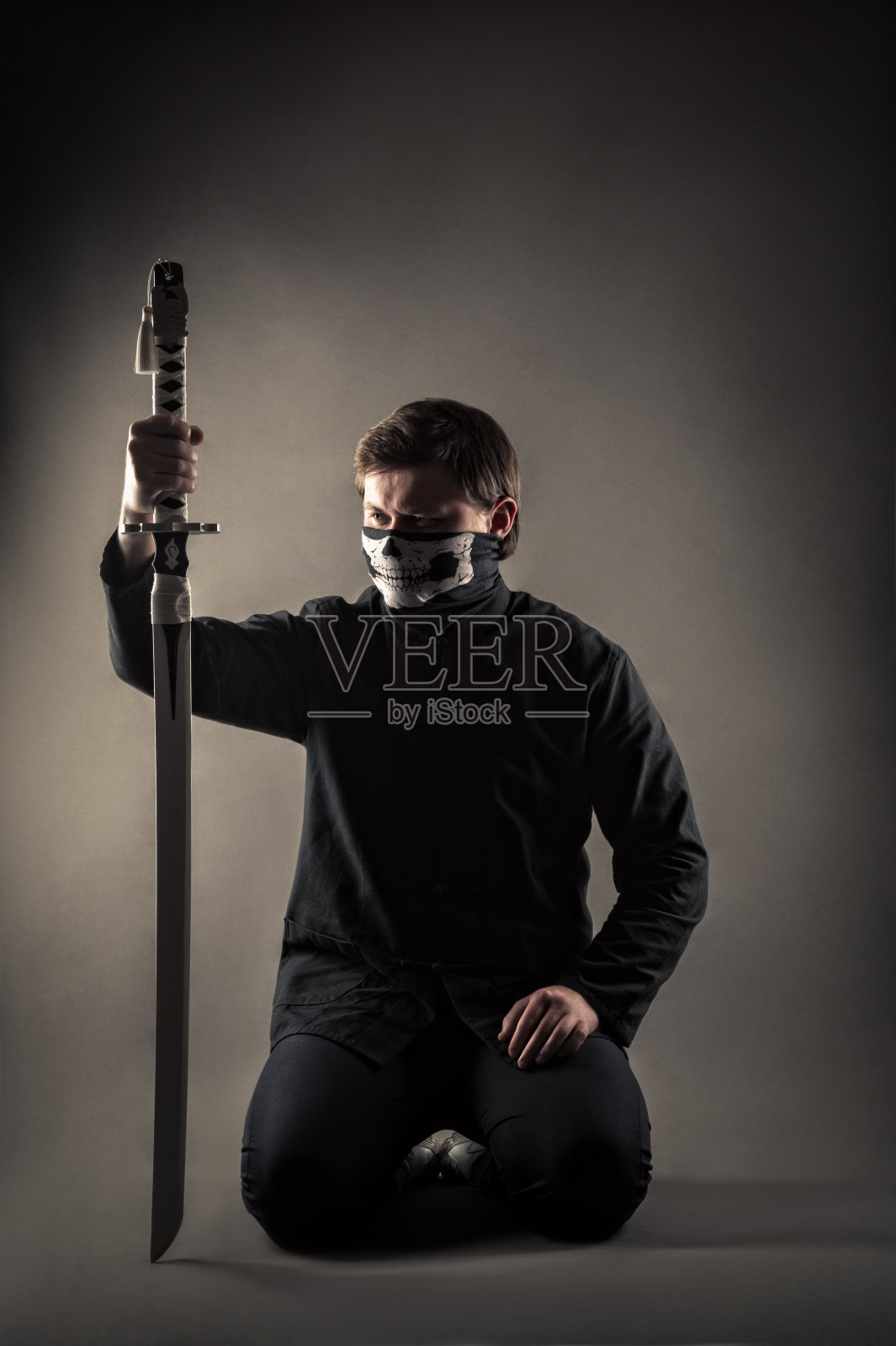 膝盖上坐着武士刀的男性战士照片摄影图片