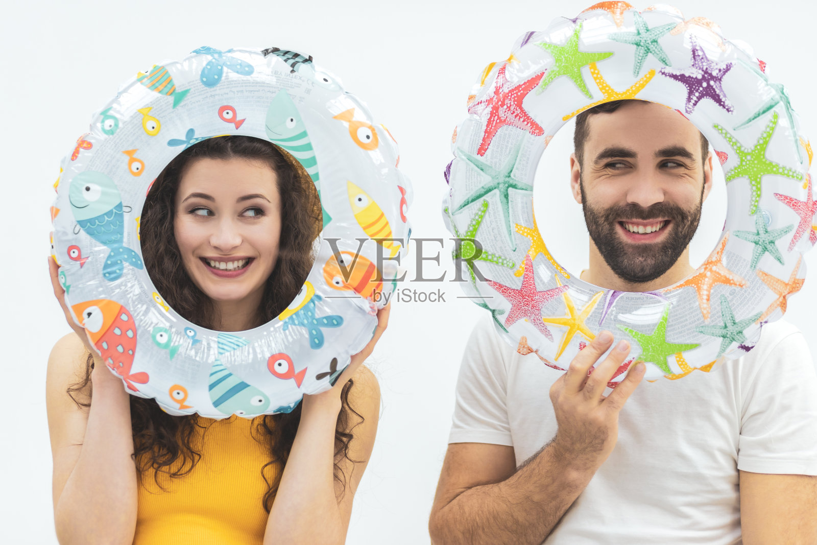 漂亮的年轻夫妇拿着救生衣遮住脸。照片摄影图片