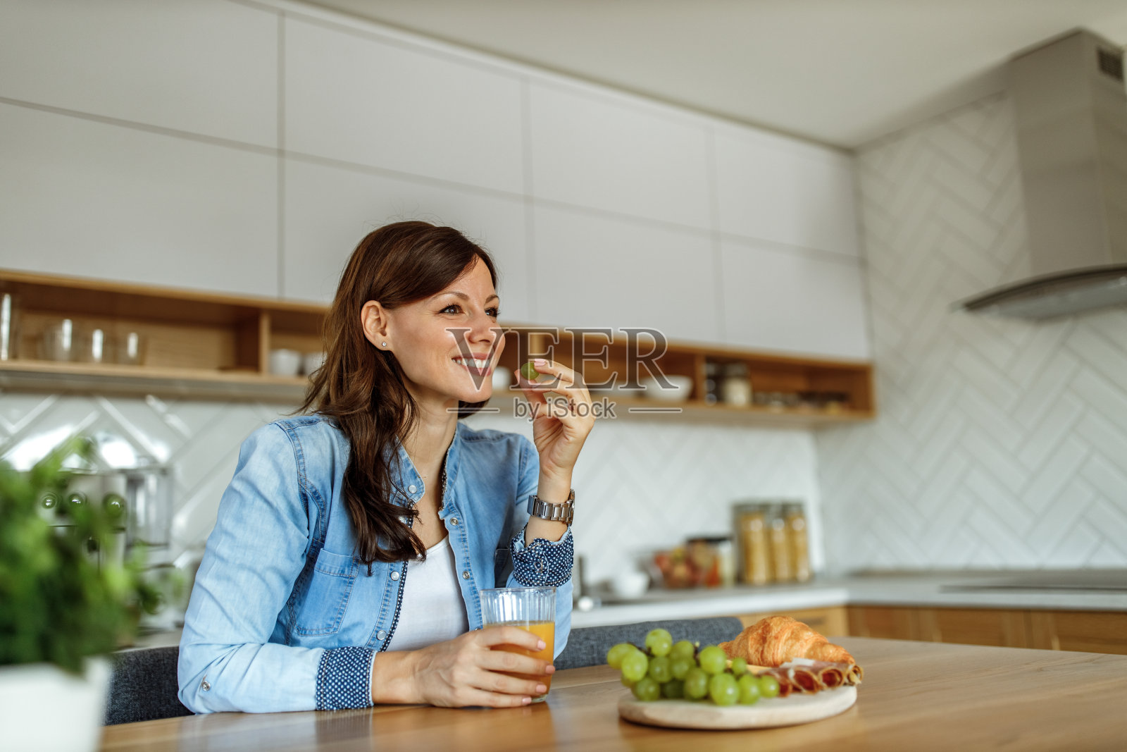 坐在现代化的厨房里。微笑的脸。照片摄影图片