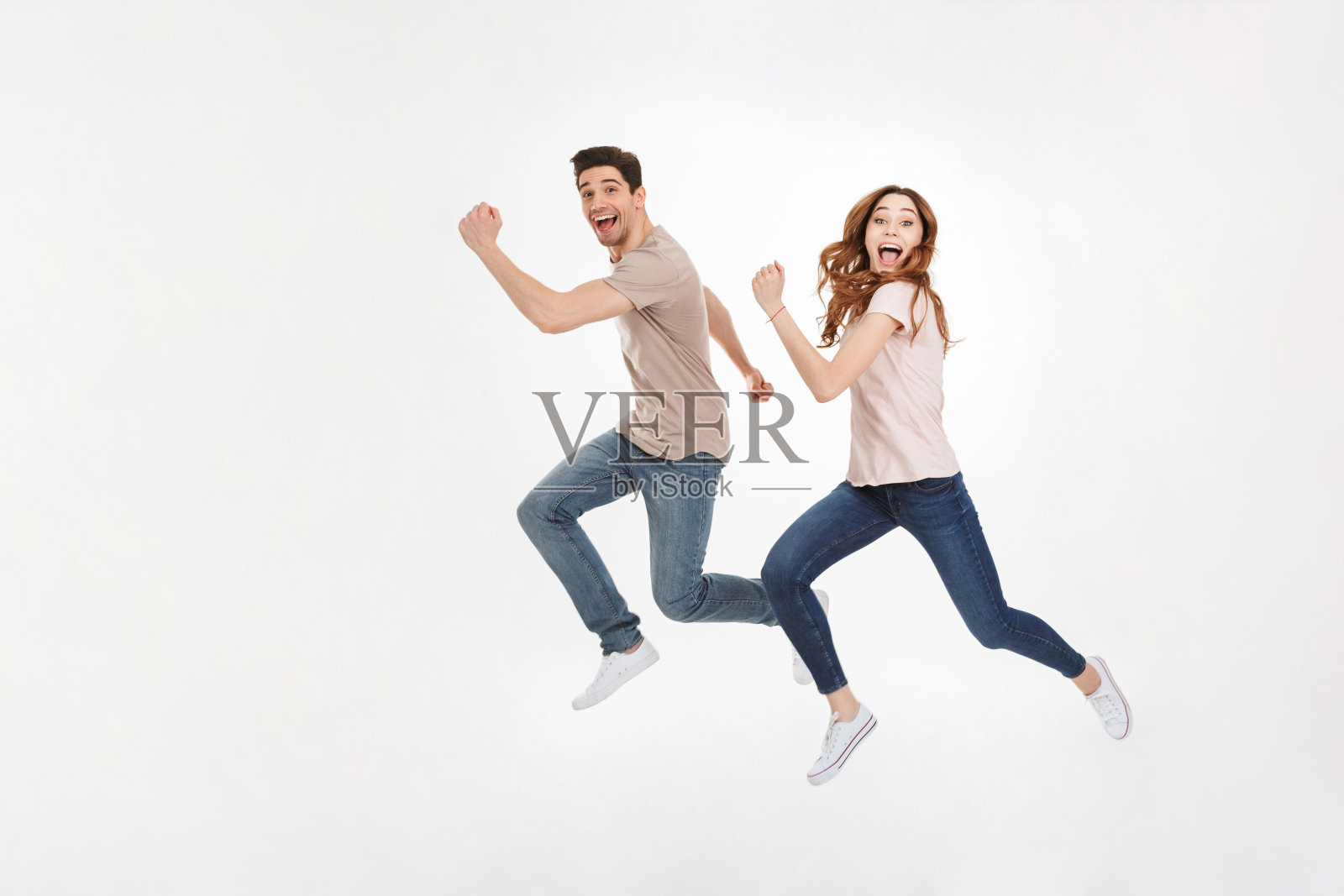 这对幸福的男女穿着休闲t恤在镜头前奔跑，面带微笑，在白色的背景下与世隔绝照片摄影图片