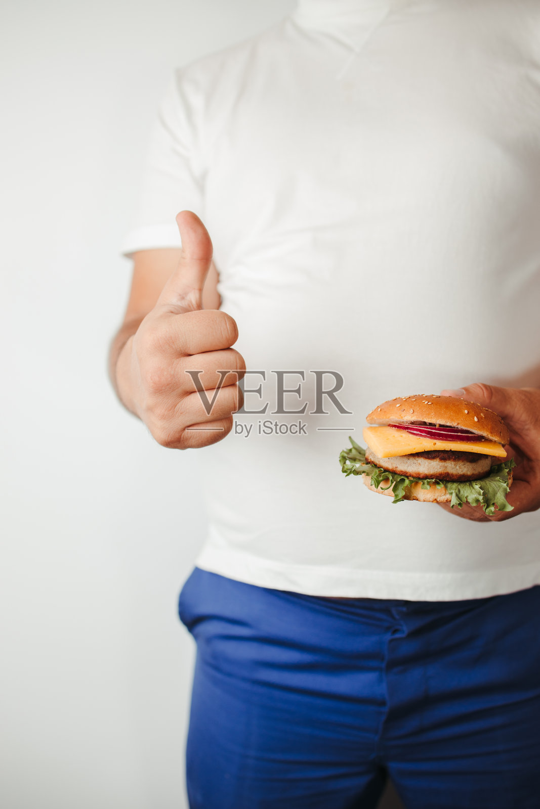 拿着汉堡竖起大拇指的胖子照片摄影图片