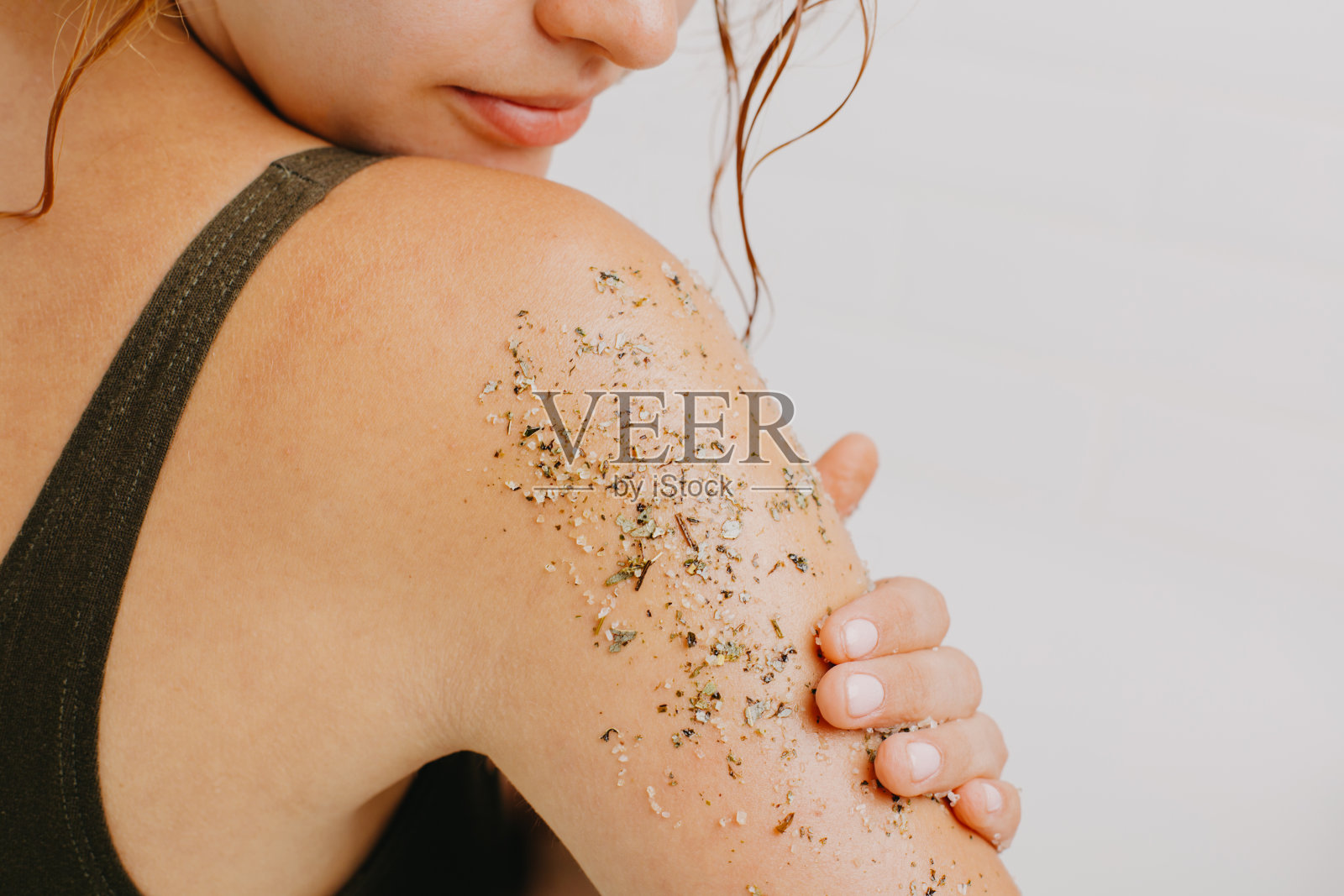 在白色背景上使用身体磨砂膏的女人。照片摄影图片