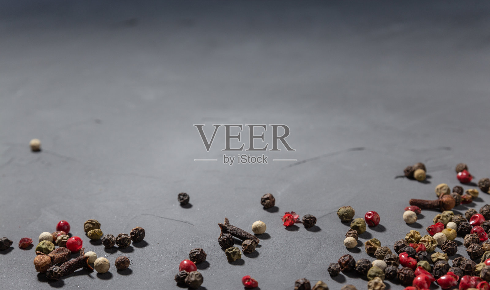 胡椒粉和丁香。黑色，红色和白色的花椒孤立在黑色的石头背景。特写,复制空间照片摄影图片