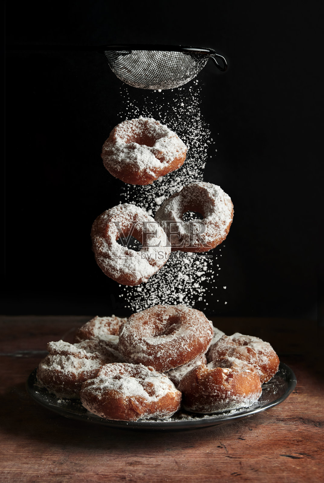 自制的甜甜圈上撒着糖霜。黑色背景照片摄影图片