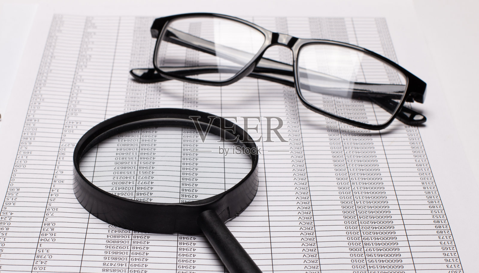黑框眼镜和放大镜躺在报告上照片摄影图片
