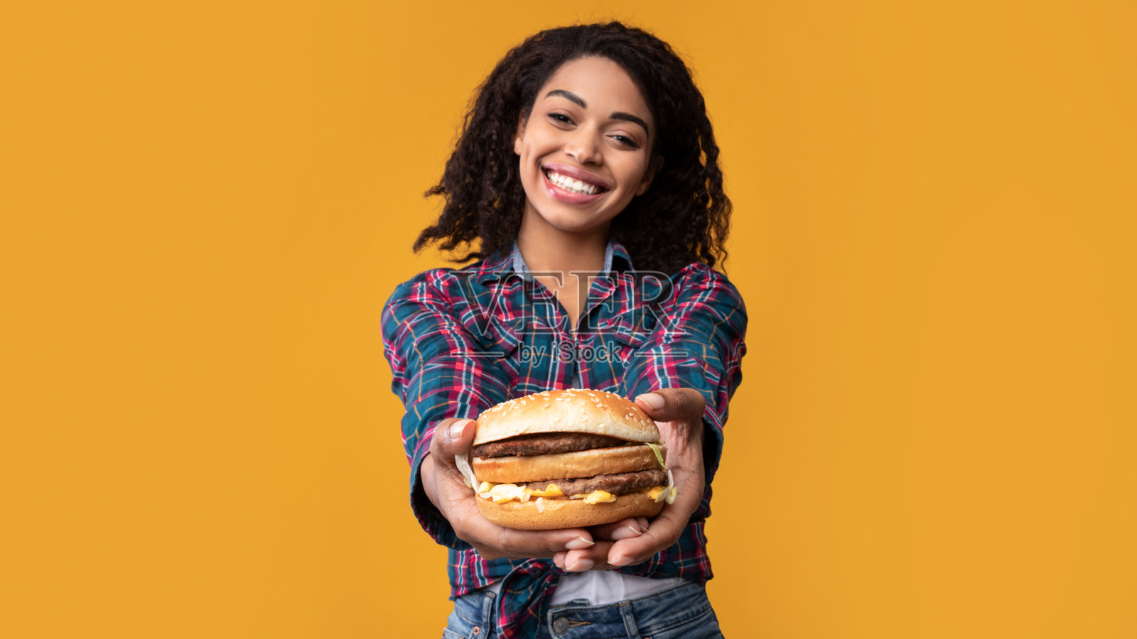 有趣的非裔美国女士在工作室里给汉堡照片摄影图片