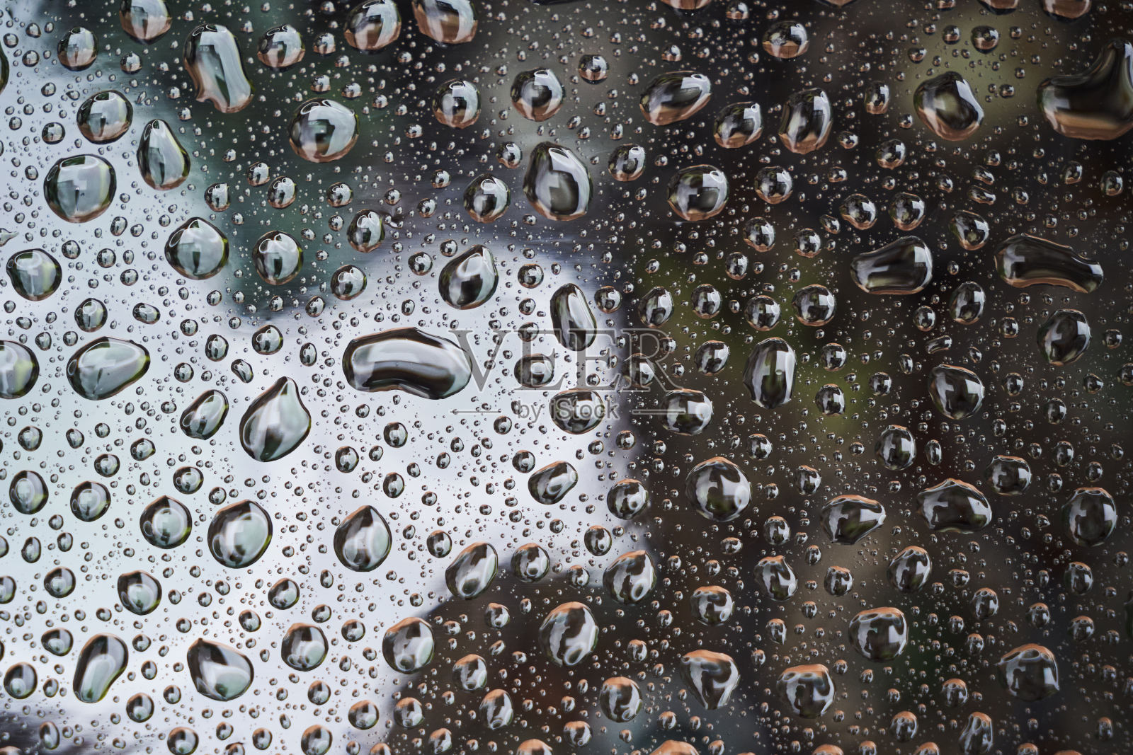 雨滴落在玻璃背景上。反射在玻璃上的雨滴照片摄影图片
