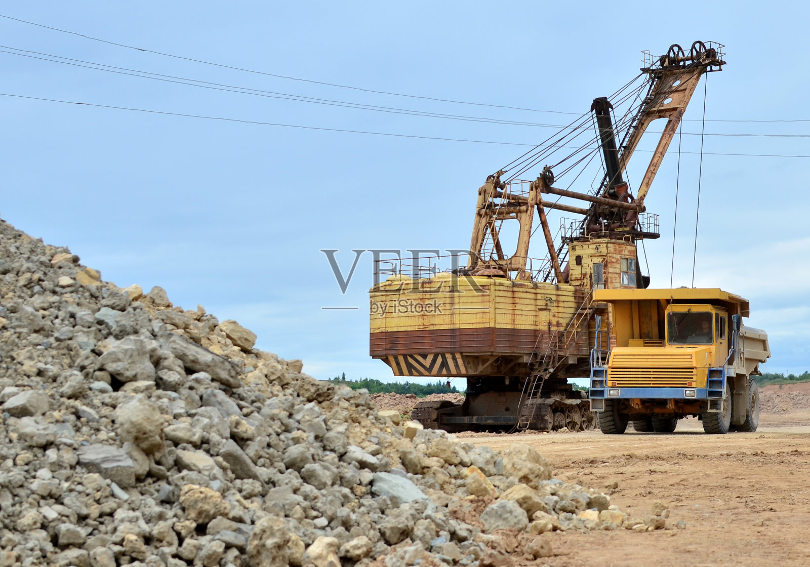 采矿卡车和挖掘机在石灰石露天矿工作。照片摄影图片