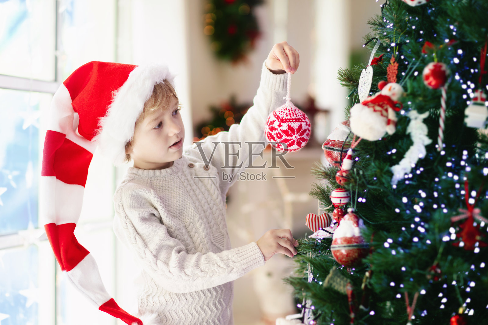 孩子装饰圣诞树。圣诞前夜的孩子。照片摄影图片