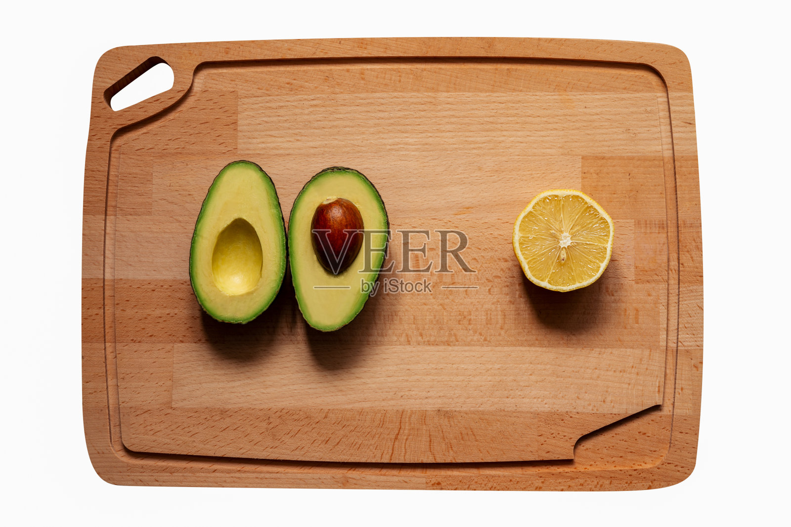 新鲜、成熟、完美、营养丰富的鳄梨，用酸橙和柠檬切成两半。从上往下看木质砧板背景。照片摄影图片