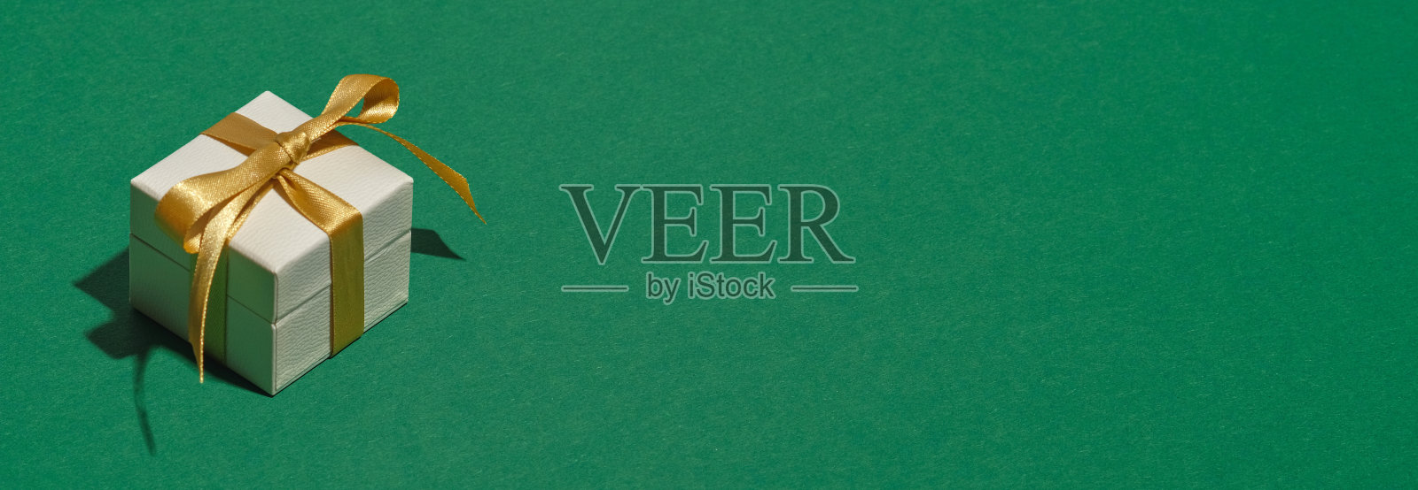 白色礼盒与黄色丝带蝴蝶结在绿色背景与复制空间。圣诞横幅模型，标题设计，贺卡模板。照片摄影图片