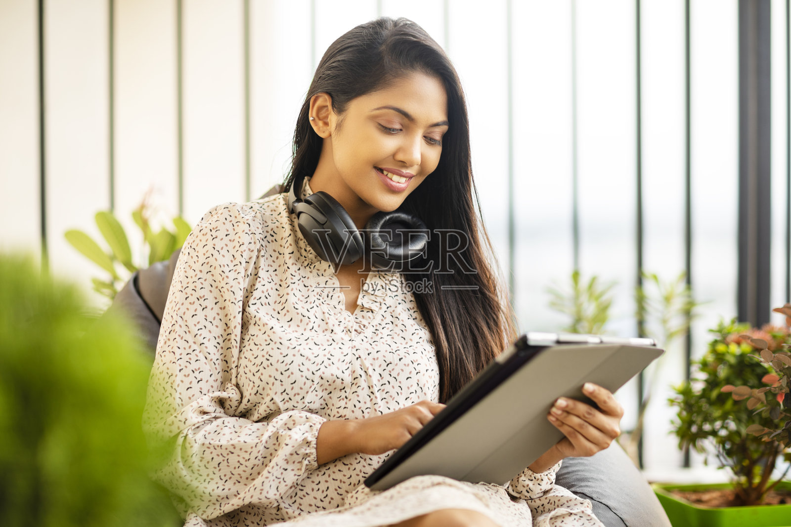 漂亮的印度年轻女子使用数字平板电脑和耳机照片摄影图片
