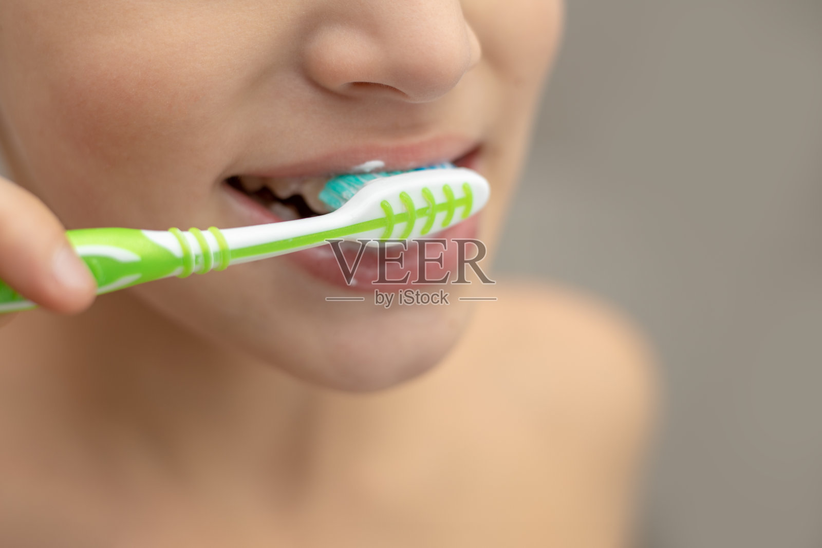 照片的十岁前英俊的男孩刷牙他的强壮的白色健康的牙齿鬼脸近距离的肖像在浴室。居家生活，牙科理念照片摄影图片