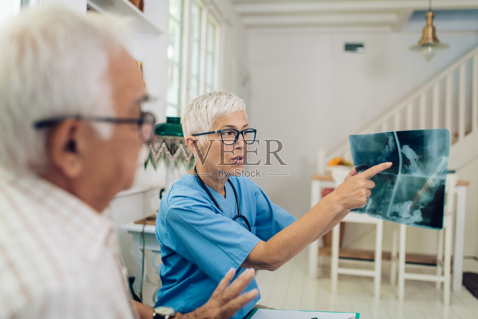 医生给她的老年病人看x光片照片摄影图片