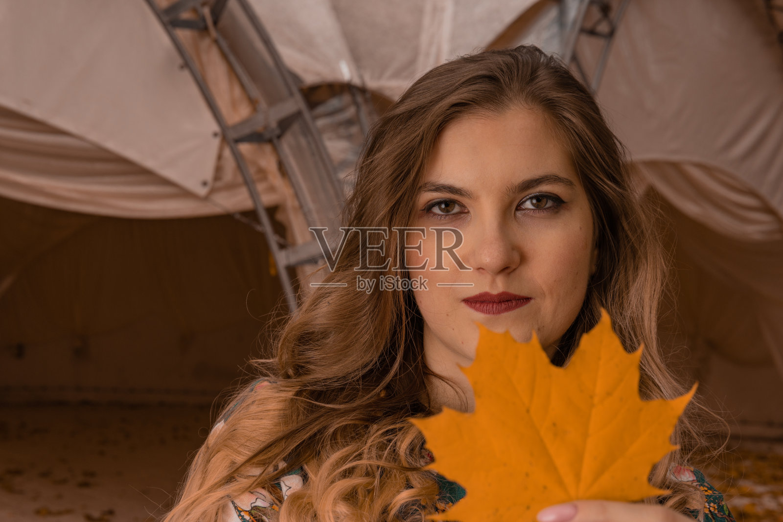 在秋天的公园里，一个帐篷背景上有枫叶的女孩照片摄影图片