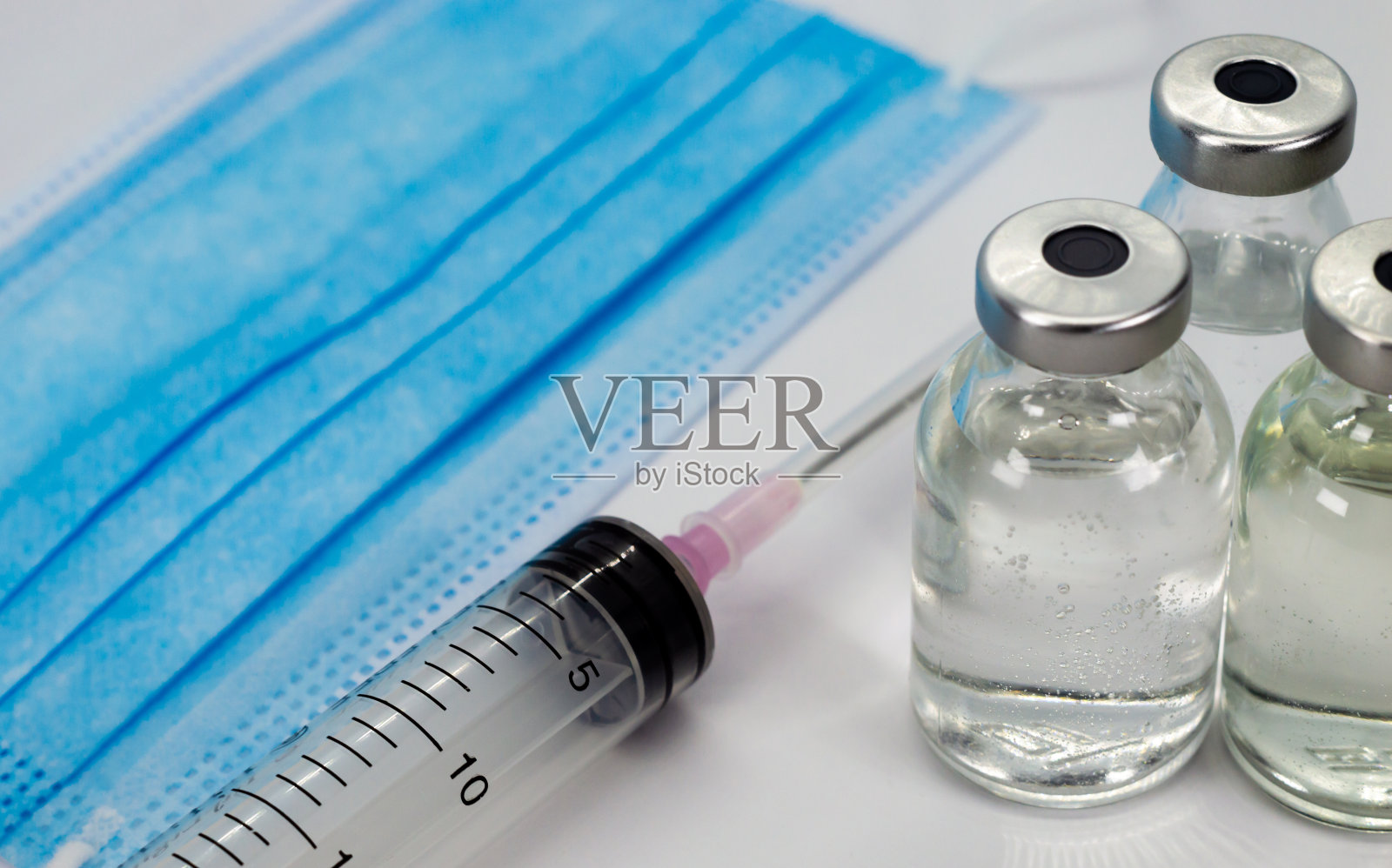 疫苗瓶，注射器和蓝色医用口罩照片摄影图片