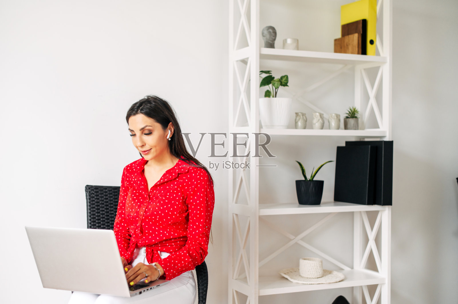 迷人的年轻女子坐在室内，手提电脑照片摄影图片