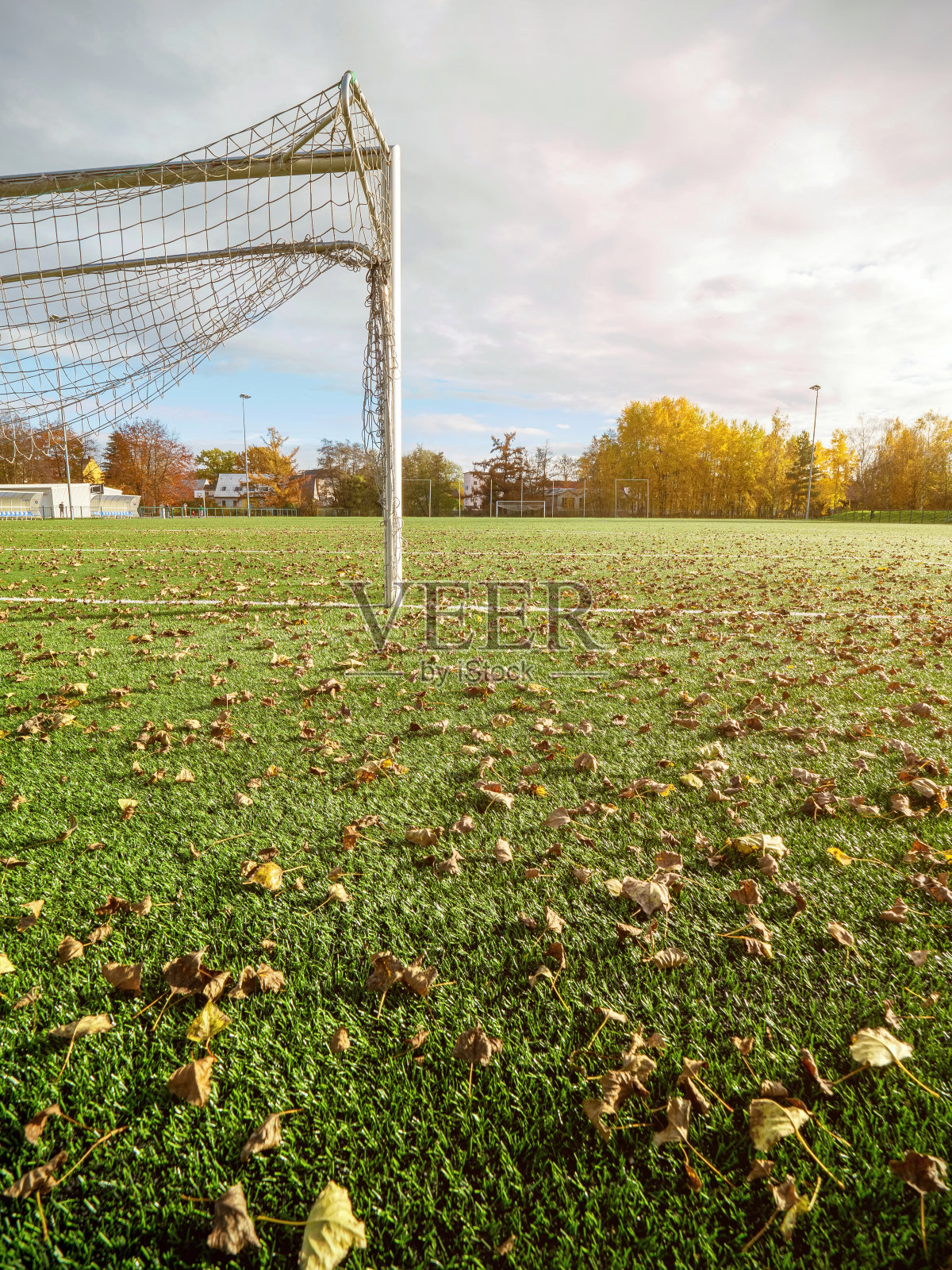 缤纷的落叶飘落在空旷的足球场上。秋天的季节照片摄影图片