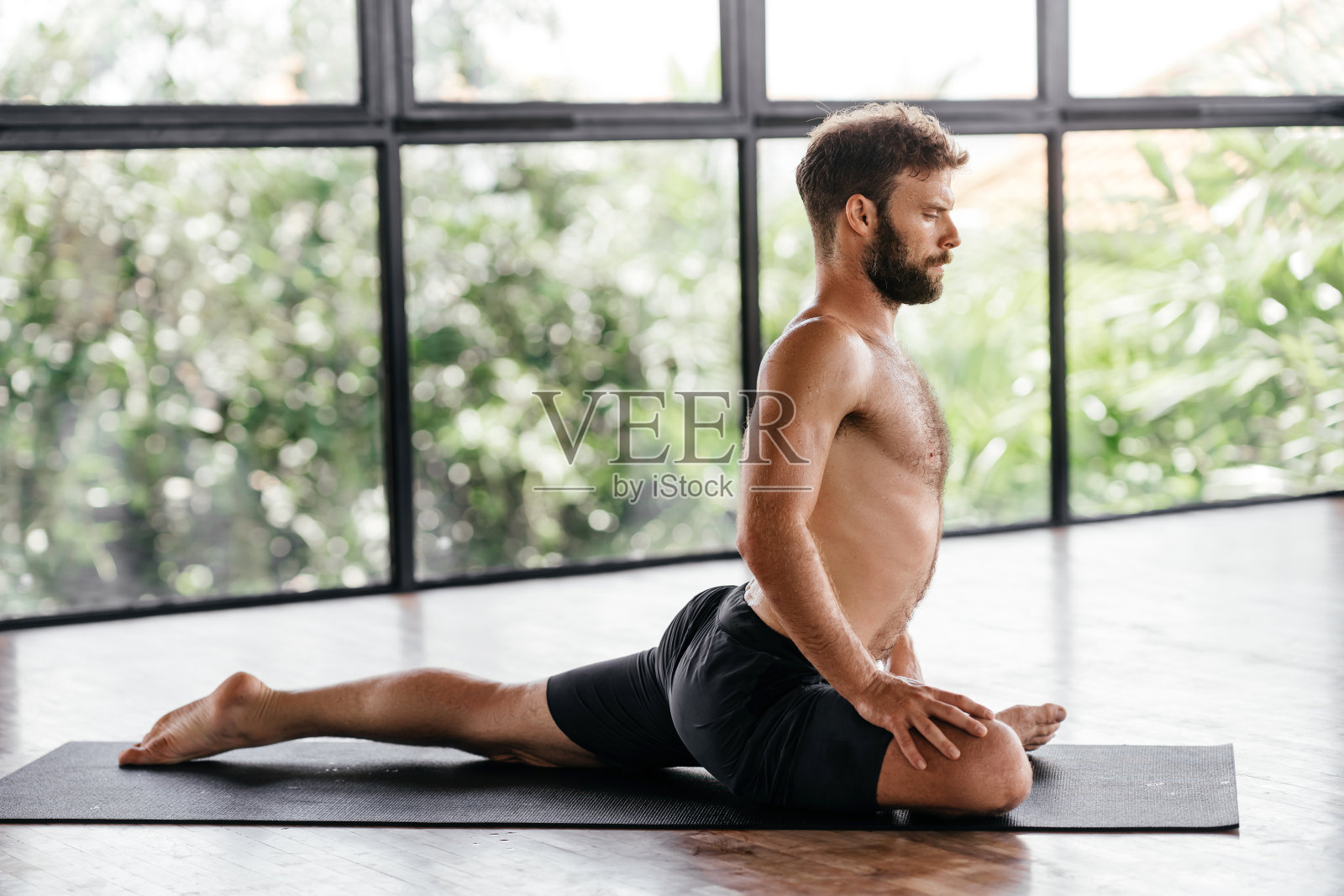 瑜伽男在工作室的窗户前锻炼照片摄影图片