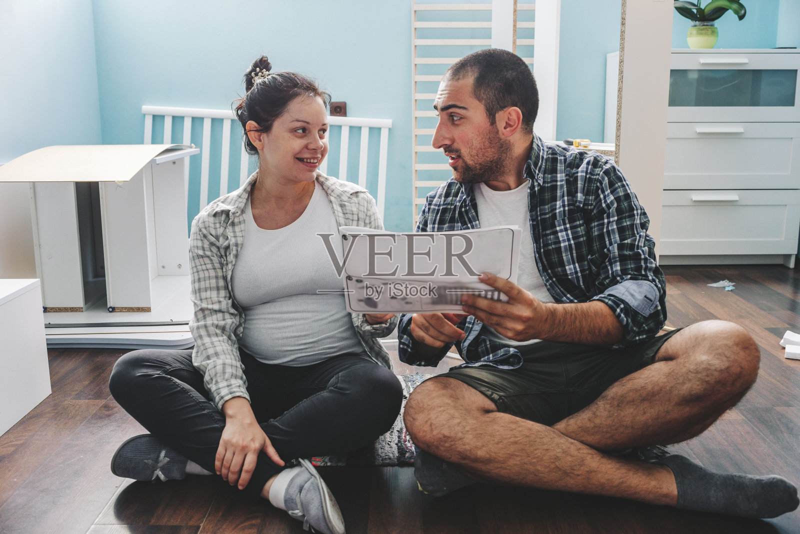 一对年轻夫妇在组装婴儿床照片摄影图片