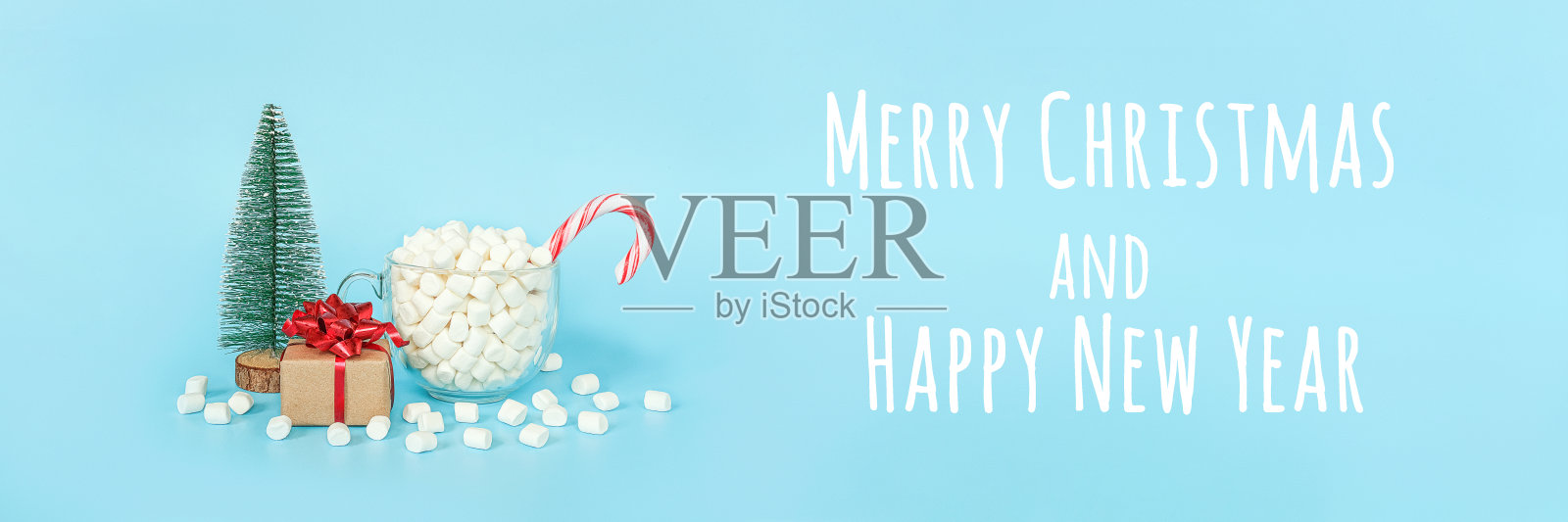 圣诞快乐，新年快乐明信片。礼盒，圣诞树和一杯棉花糖红色棒棒糖在蓝色背景。节日的概念。前视图,横幅照片摄影图片