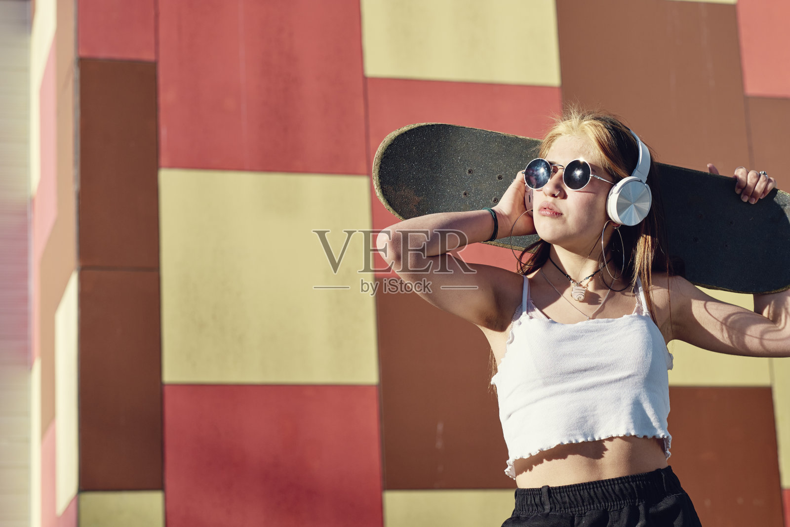 迷人的年轻女子脖子上挂着滑板照片摄影图片