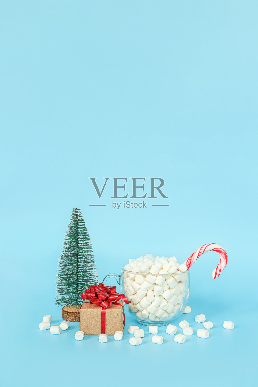 圣诞快乐，新年快乐明信片。礼盒，圣诞树和一杯棉花糖红色棒棒糖在蓝色背景。节日的概念。正面视图，贺卡复制空间照片摄影图片