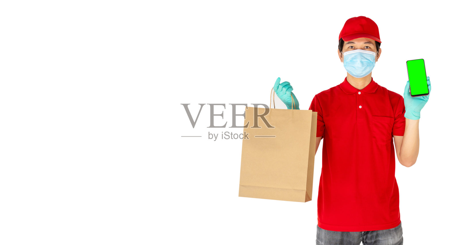 快递员员工戴红帽t恤制服口罩手套手持牛皮纸包食品和电话隔离在白色背景，服务隔离大流行性冠状病毒流感概念照片摄影图片