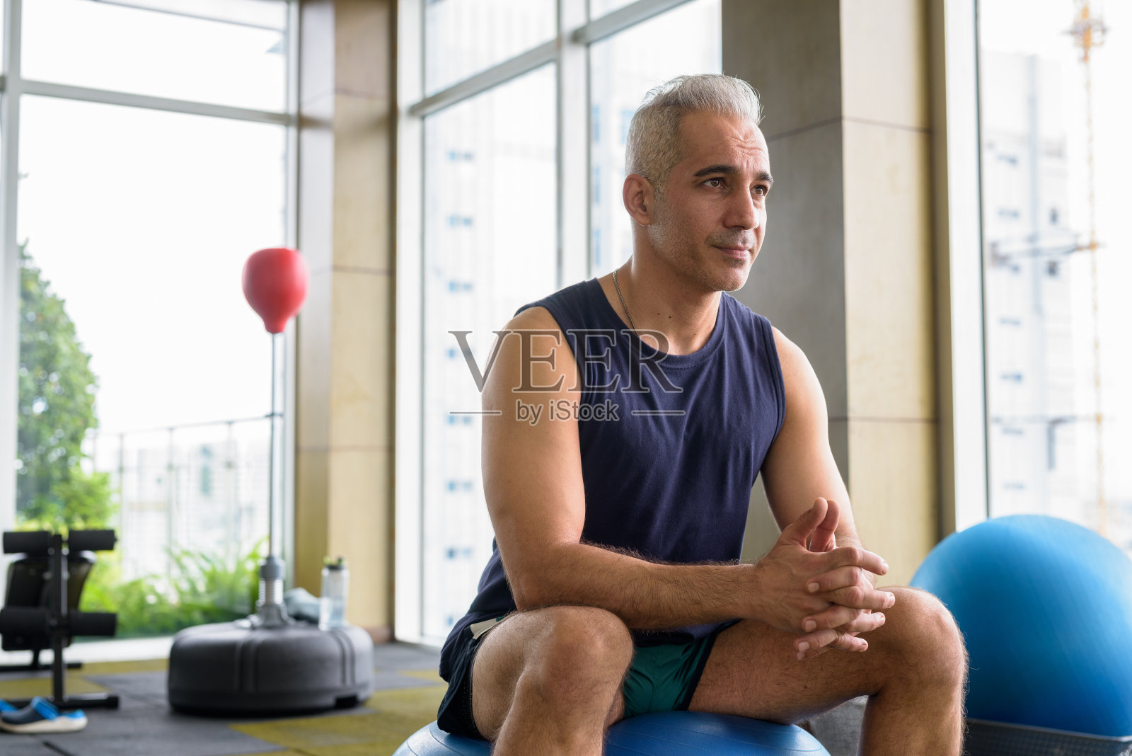 在健身房使用瑜伽球的英俊波斯中年男人肖像照片摄影图片