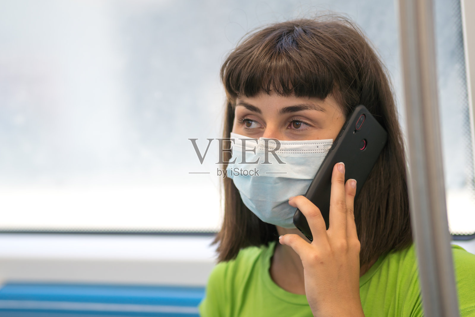 年轻女子戴着口罩在公共交通工具上打电话照片摄影图片