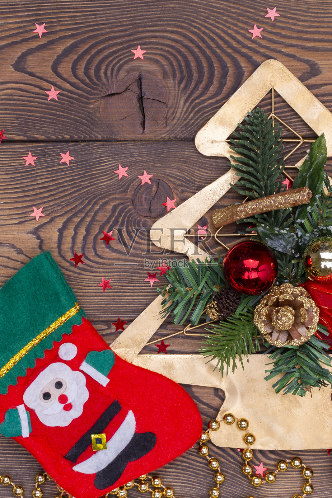 红色的毡子长袜，上面有冷杉树枝和圣诞装饰品，雪花，木桌上的珠子。俯视图，复制空间，垂直照片。照片摄影图片