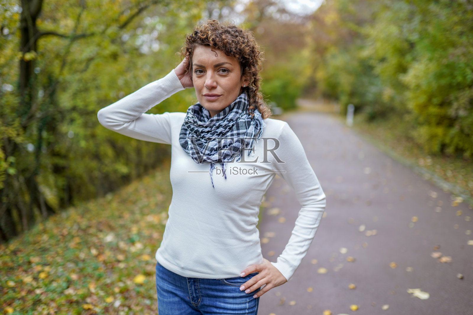 年轻女子与卷头发和围巾摆姿势的自然照片摄影图片